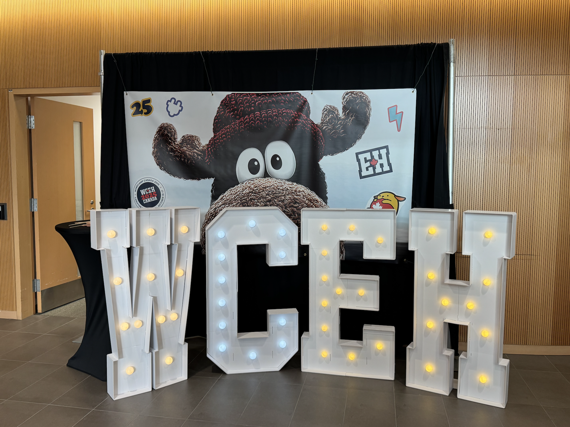 A photo backdrop of a moose. In front of it, light up signs with letters spelling "WCEH"